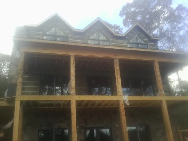 Dormers and porch framing on a large log home under construction — Roof Coating work by our crew in Rewey