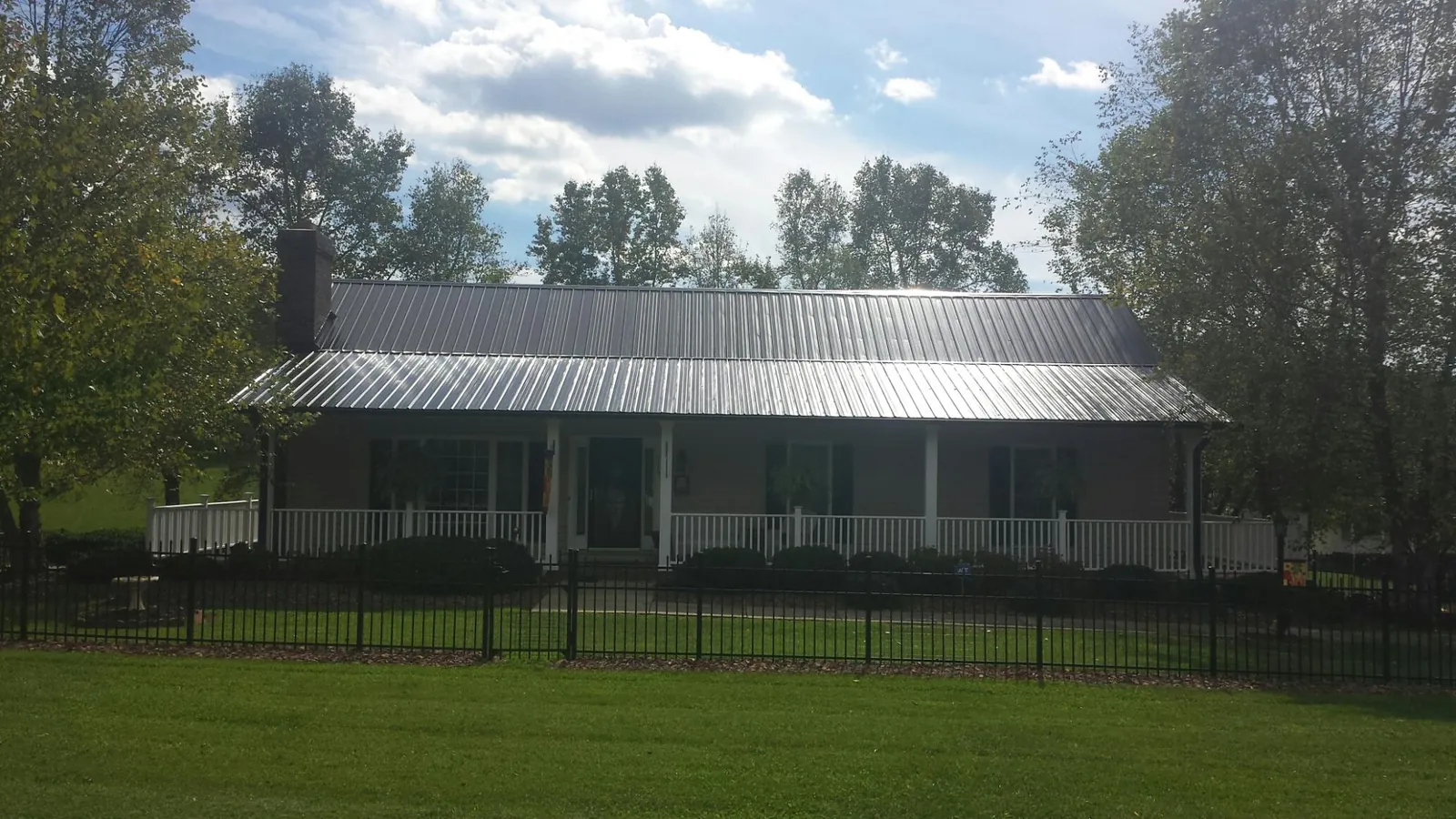Gray metal roof on a brick ranch with a full width front porch — Gutter Guard Installation work by our crew in Rewey