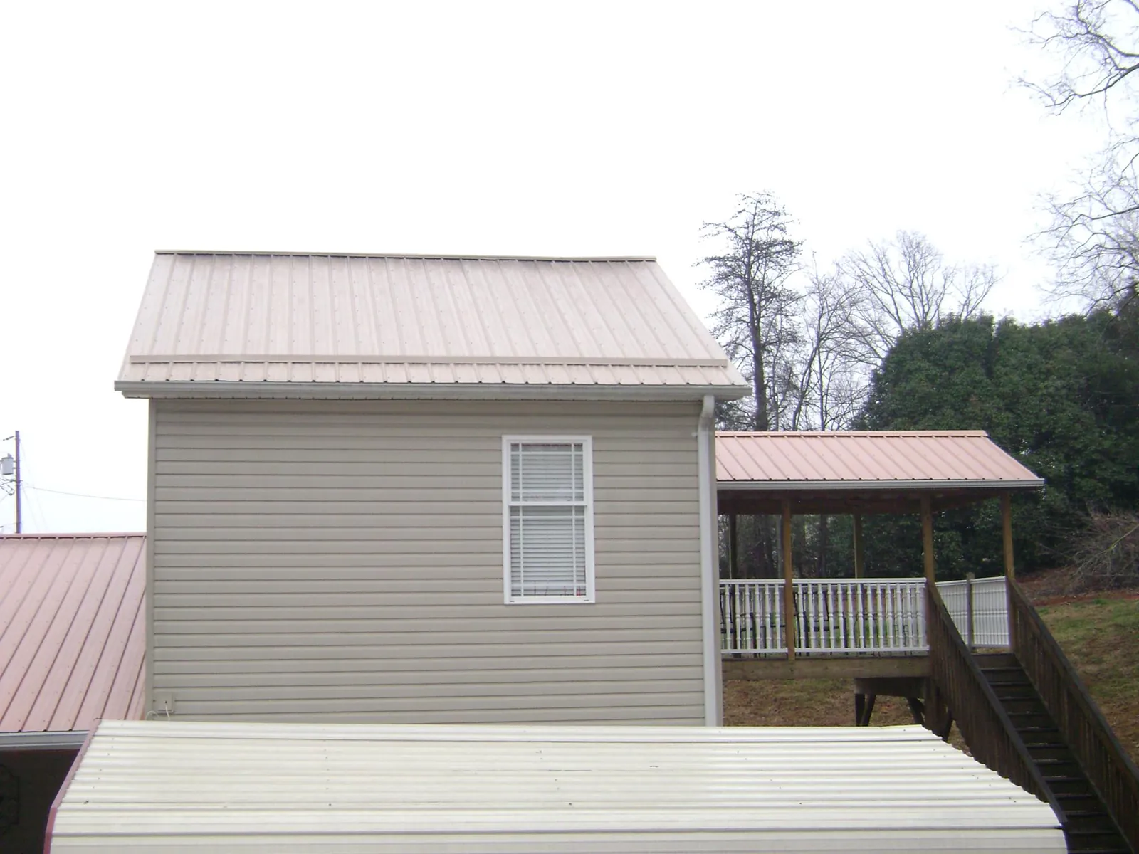 Tan metal roofs on a two story addition and attached porch, from a Roof Replacement job in Rewey