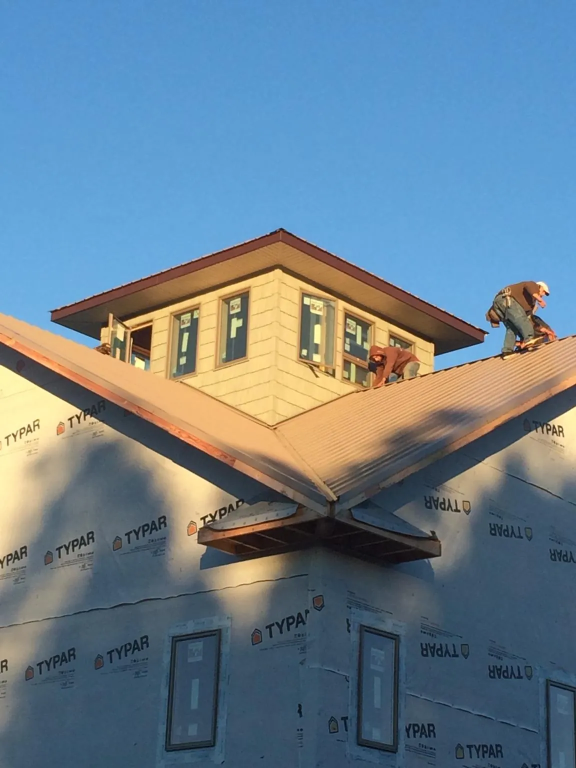 Roofers working around a rooftop cupola on a new metal roof at sunset — Roof Waterproofing in Rewey by Roofing Brothers